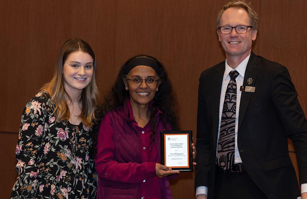 Indira Rajagopal receiving award from student and Roy Haggerty