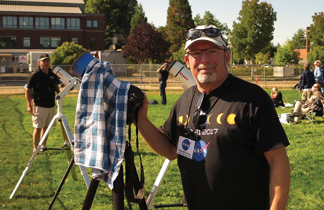 Randall Milstein working microscope in field with viewers of Solar Eclipse