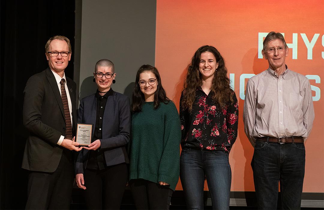 female students receiving award from science faculty on stage