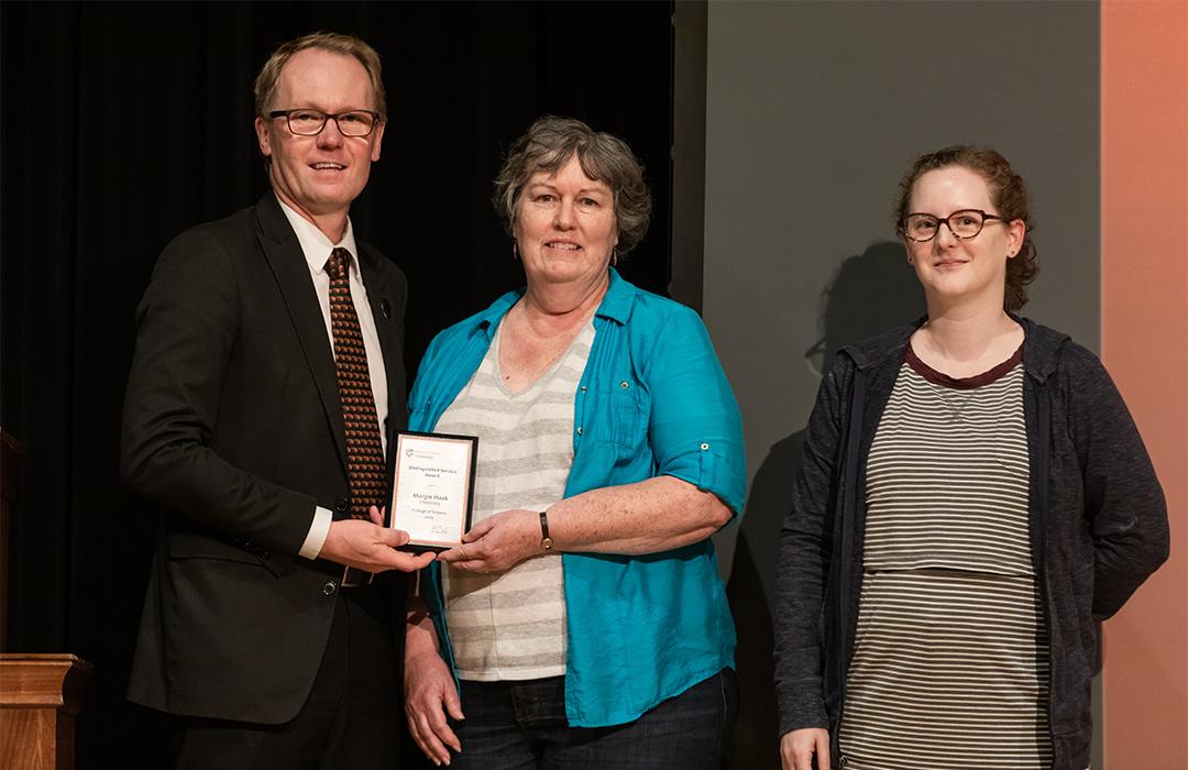 Margie Haak receiving award from faulty on stage