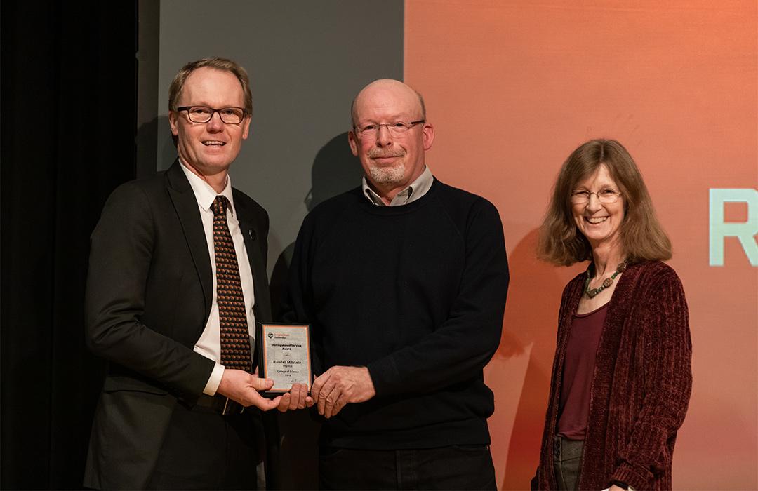 Randall Milstein receiving award from colleagues on stage