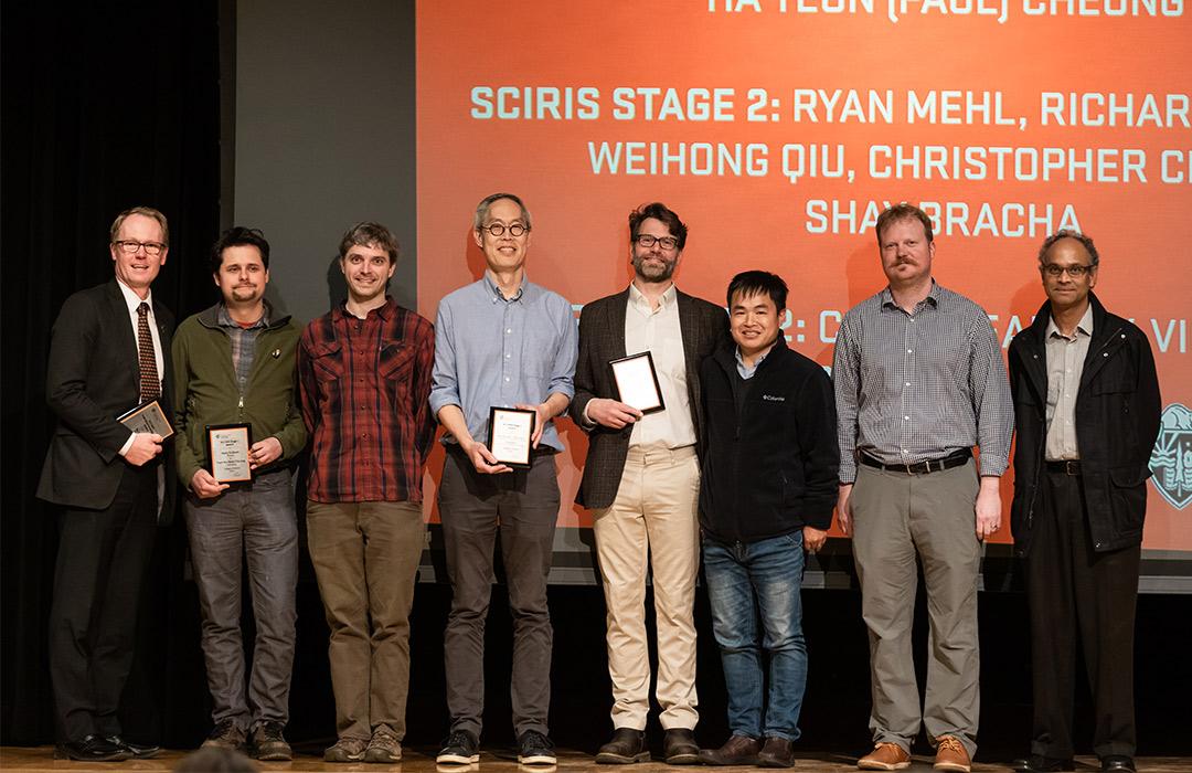 award recipients holding up awards on stage with colleagues