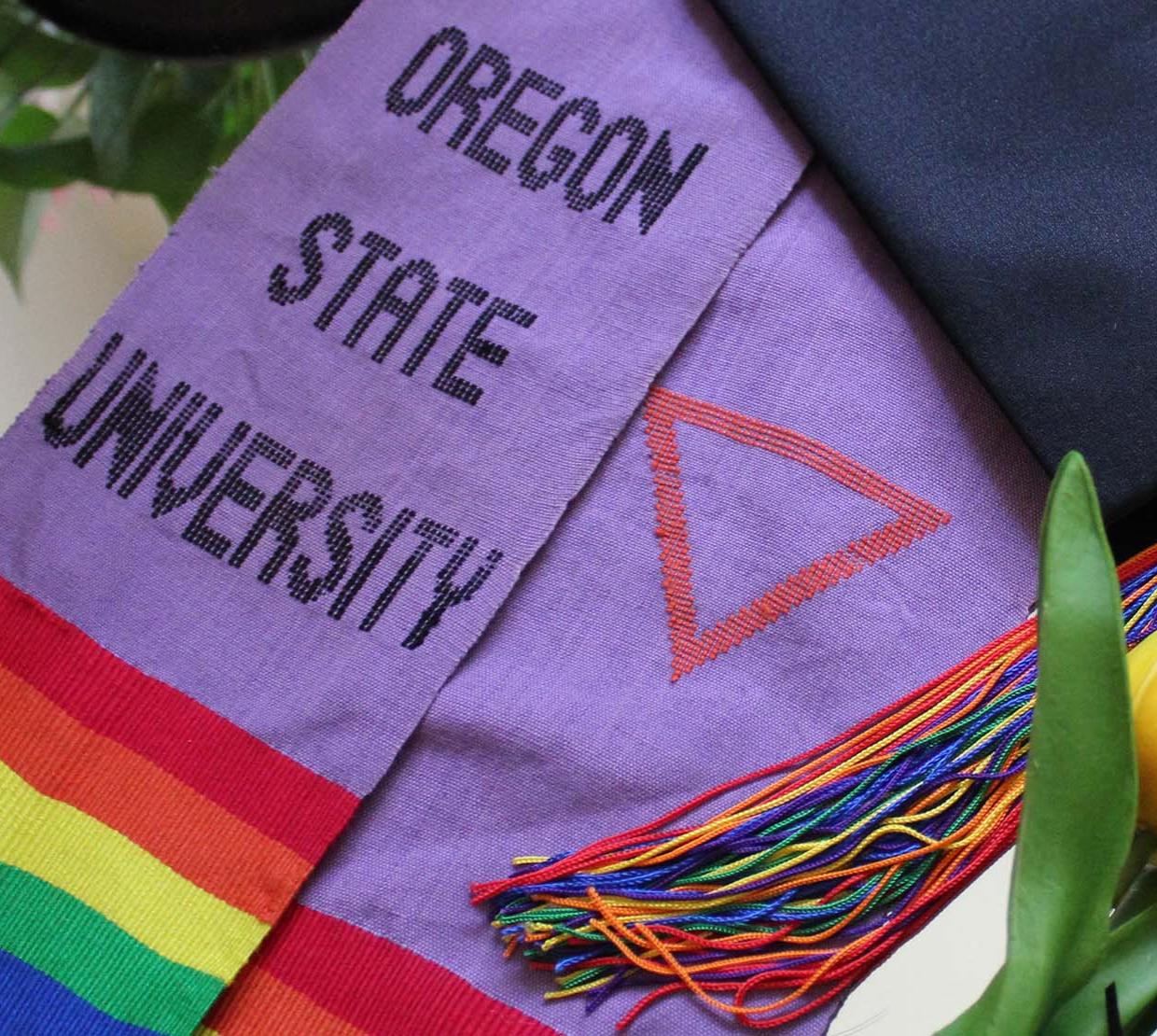 A graduation cap with a rainbow pride flag coming off the back