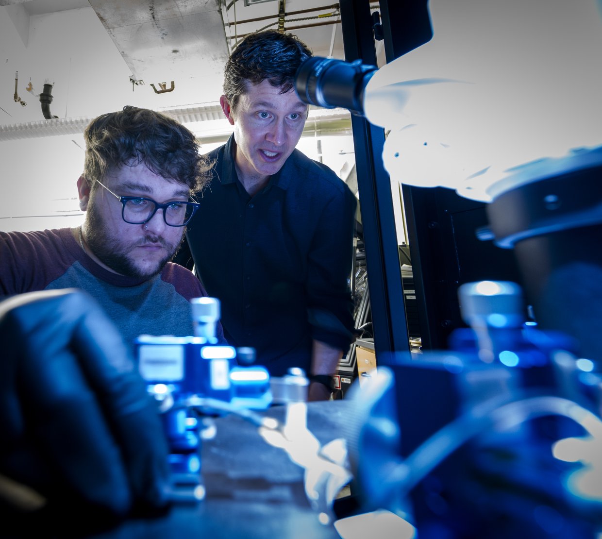 A professor shows a student how to use a piece of lab technology.