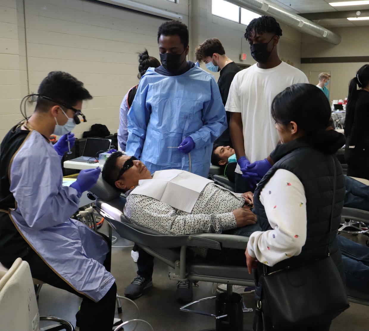 Students help a community member receive dental care.