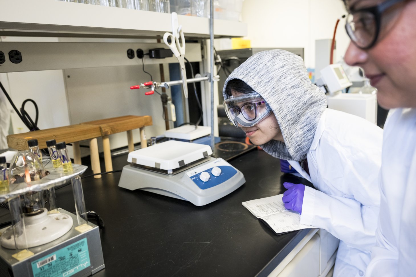 One camper decked out in goggles eagerly observes a bunch of test tubes linked up to a bulb with wires in a chemistry lab at Oregon State University.