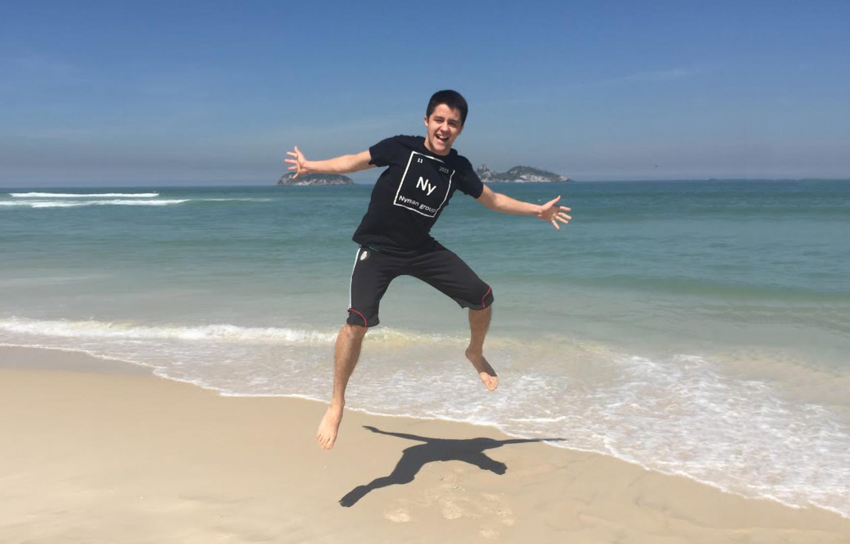 Collin Muniz wearing a chemistry t-shirt jumping on the beach