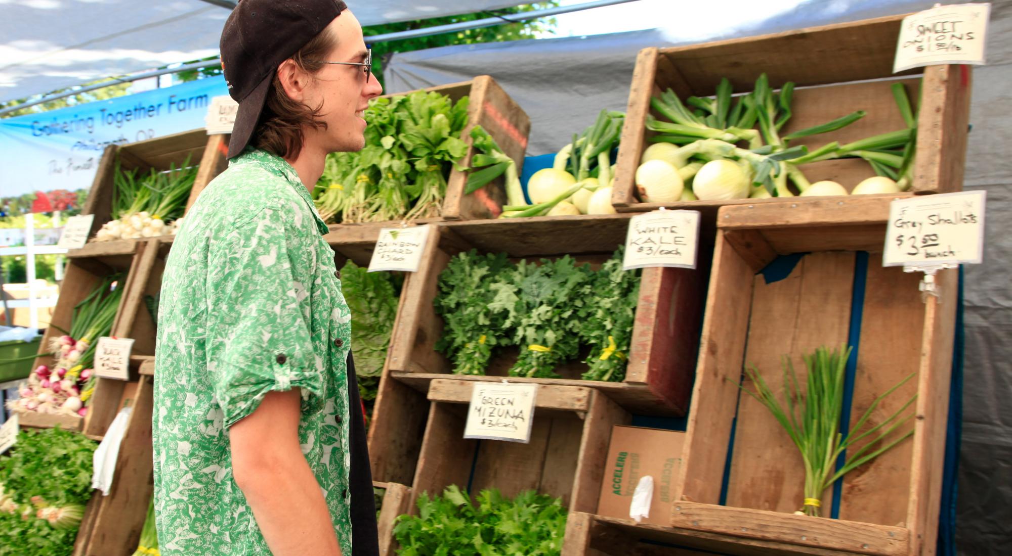 A young man considering produce at the farmer's market