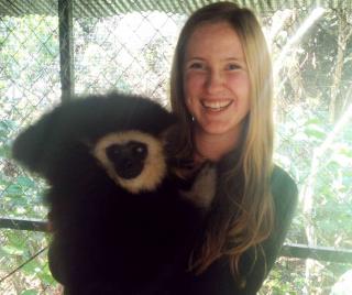 Karianna Crowder holding a white-cheeked gibbon in enclosure