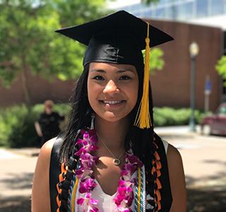 Chloe Villagomez standing on campus wearing Graduation cap