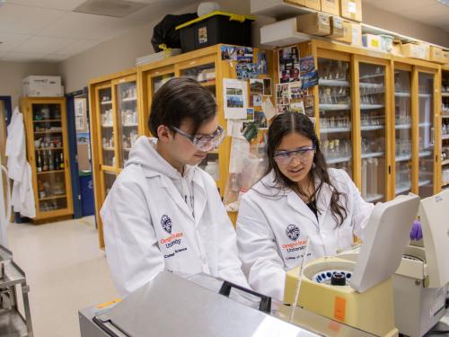 Two students working with equipment in a lab.
