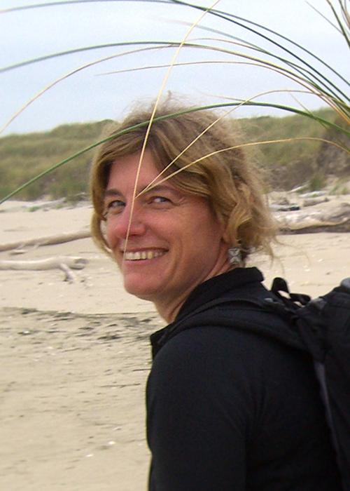 Sally Hacker walking along beach with grass samples in backpack