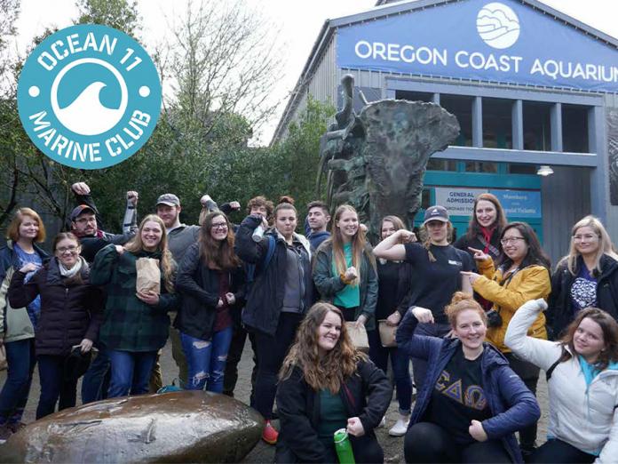Ocean11 club members taking group picture in front of Oregon Coast Aquarium.