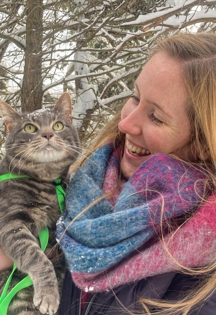 Karianna Crowder hugging her cat while in a snowy forest.