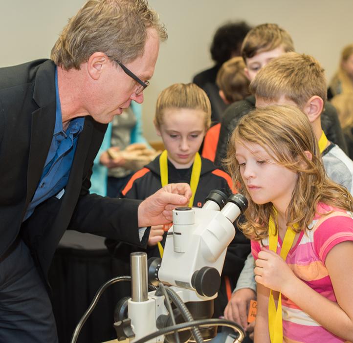 Roy Haggerty showing a young girl how to look into a microscope