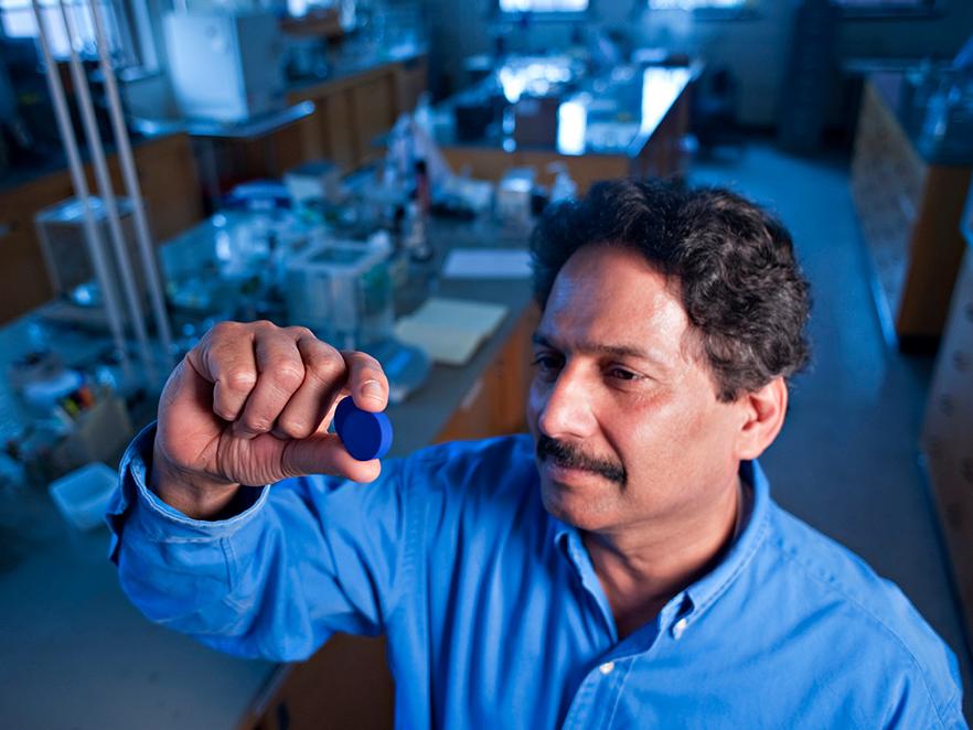 Mas Subramanian holding blue pigment in lab